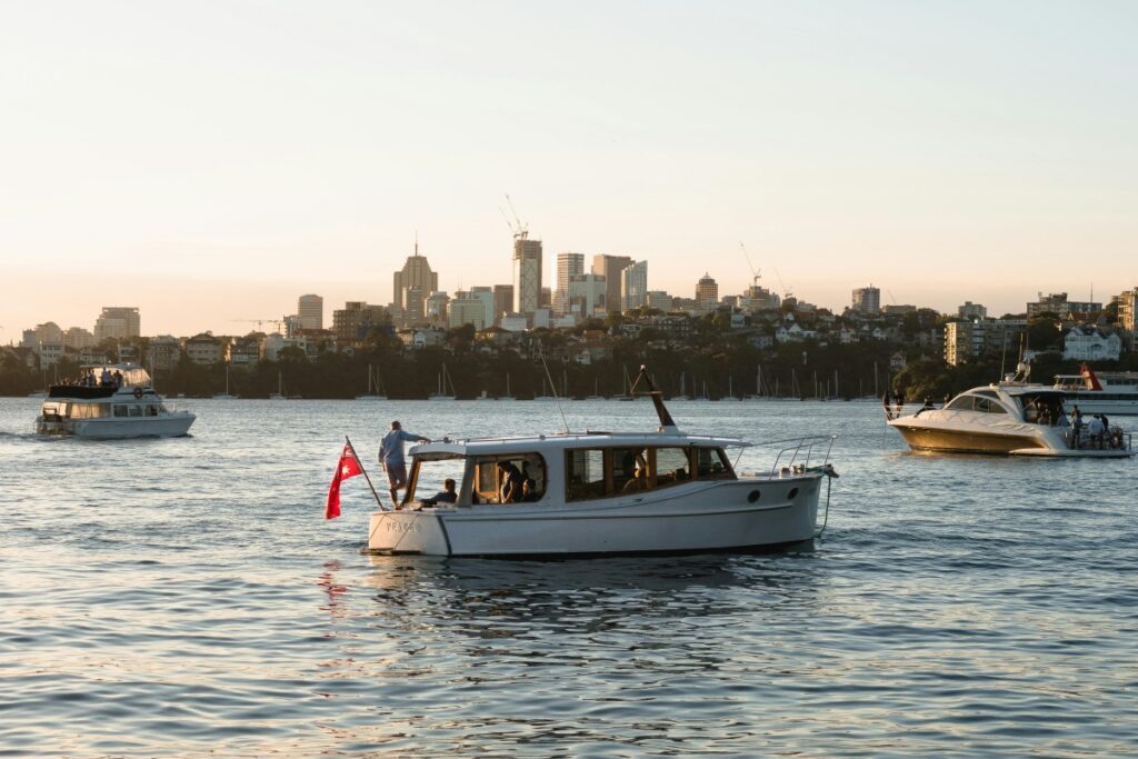 This image shows boats floating on a body of water with the skyline of an Australian city in the background. There are people on the boats, enjoying what appears to be a pleasant time. One boat has a red flag fluttering at the stern. For "Instagram Marketing in Australia Best Practices", if your brand is related to boating, tourism, or waterfront real - estate in Australia, this image can be a great asset. Use it to create engaging Instagram posts. Highlight the unique Australian boating experience, or the allure of the city's waterfront. Incorporate relevant hashtags like #AustralianBoating, #SydneyHarbour (assuming it's Sydney), and #WaterfrontLivingAustralia. Share interesting facts about the location or upcoming boating events. By creating visually appealing and relevant content, you can attract more followers and increase engagement, which are key aspects of successful Instagram marketing in Australia.