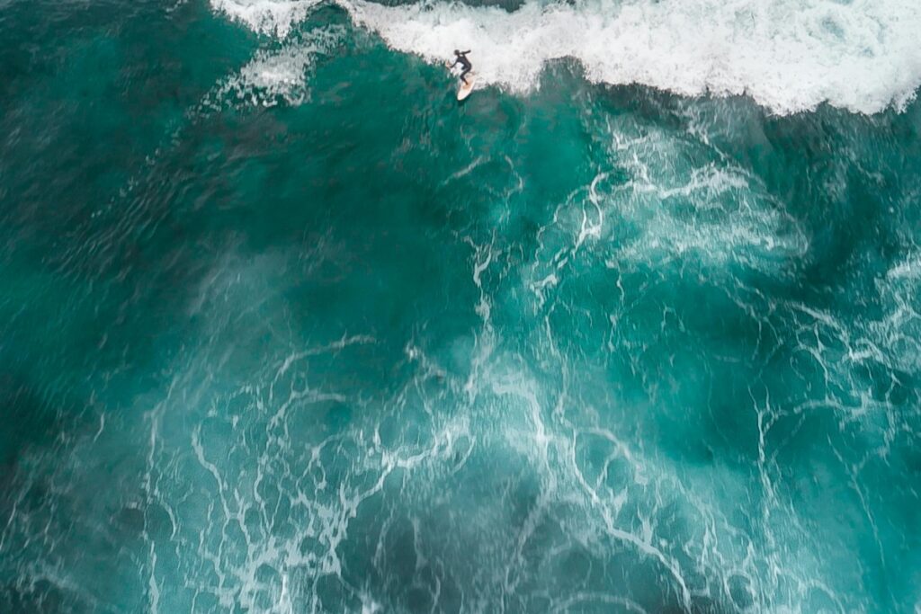 An aerial shot of a surfer riding a wave in Australia's vibrant turquoise - hued ocean. The power of the sea and the surfer's skill are on full display. Just as this surfer navigates the waves, "Mastering LinkedIn in Australia: A Comprehensive Guide to Advancing Your Career" can help you ride the currents of the professional world in Australia.